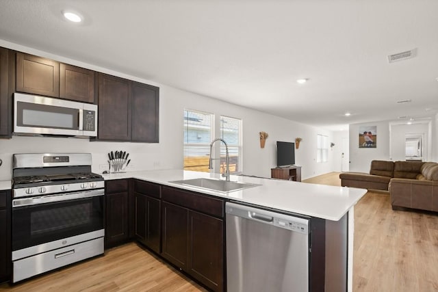197 Buenos Aires, Kyle, TX 78640 - kitchen featuring appliances with stainless steel finishes, a sink, a peninsula, light wood-style flooring, and open floor plan