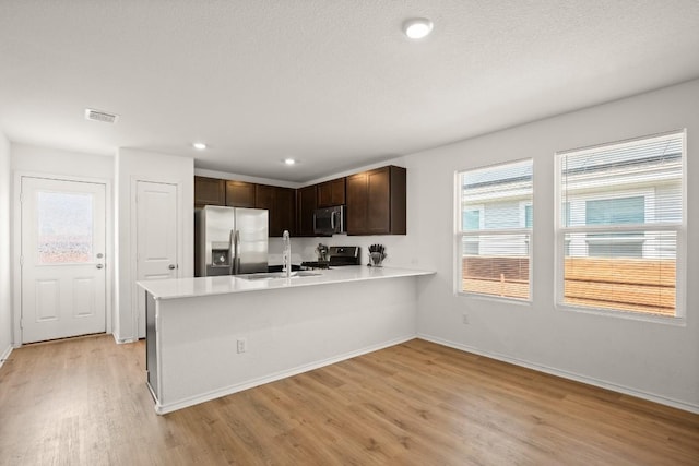 197 Buenos Aires, Kyle, TX 78640 - kitchen with appliances with stainless steel finishes, a sink, light wood-style flooring, light countertops, and dark brown cabinetry