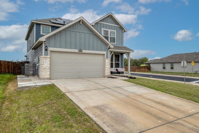 craftsman house with fence, solar panels, board and batten siding, driveway, and stone siding