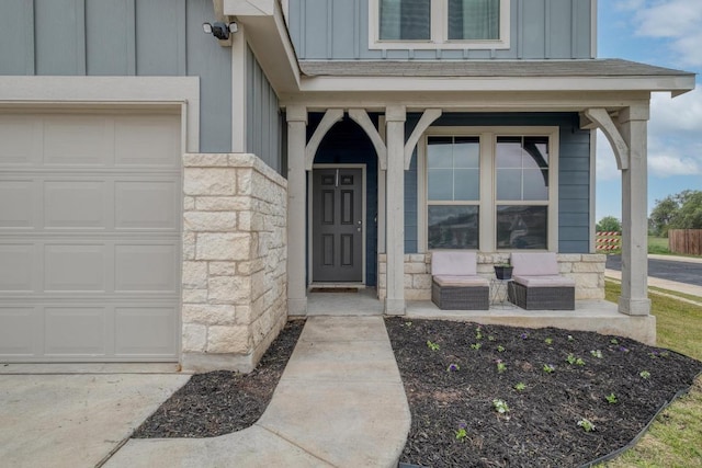 entrance to property featuring stone siding, a garage, board and batten siding, and covered porch