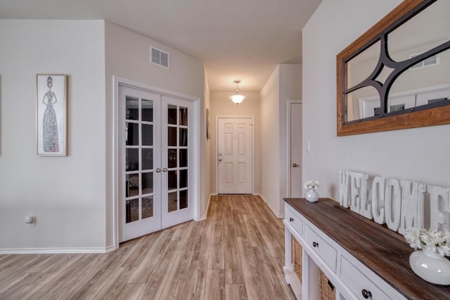 doorway to outside with visible vents, light wood finished floors, baseboards, and french doors