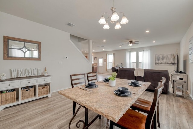 dining space with ceiling fan with notable chandelier, baseboards, light wood-style flooring, and visible vents