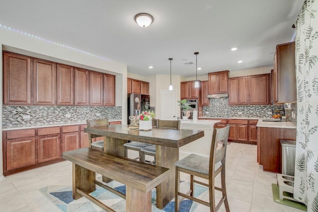 285 Kat Garnet Dr, Kyle, TX 78640 - kitchen with appliances with stainless steel finishes, decorative backsplash, brown cabinetry, pendant lighting, and recessed lighting