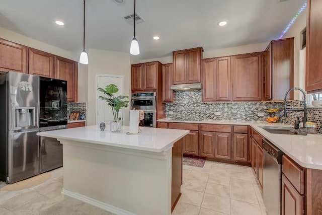 285 Kat Garnet Dr, Kyle, TX 78640 - kitchen with appliances with stainless steel finishes, decorative backsplash, light countertops, brown cabinetry, and a center island