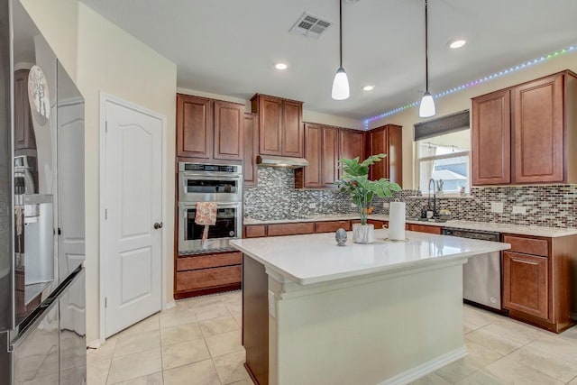 285 Kat Garnet Dr, Kyle, TX 78640 - kitchen with appliances with stainless steel finishes, tasteful backsplash, light countertops, pendant lighting, and under cabinet range hood