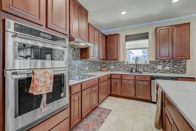 285 Kat Garnet Dr, Kyle, TX 78640 - kitchen with appliances with stainless steel finishes, decorative backsplash, light countertops, under cabinet range hood, and light tile patterned floors