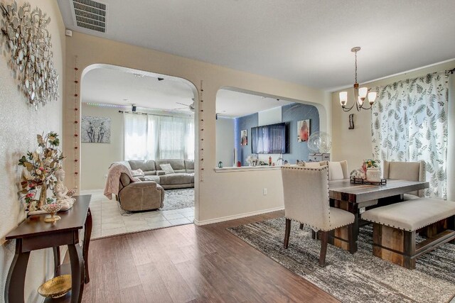 285 Kat Garnet Dr, Kyle, TX 78640 - dining space with arched walkways, a chandelier, and wood finished floors