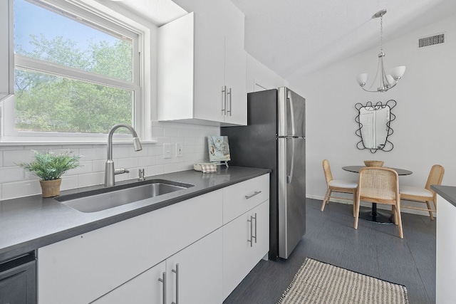 306 Tilbury Ln, Austin, TX 78745 - kitchen featuring dark countertops, backsplash, white cabinetry, and freestanding refrigerator