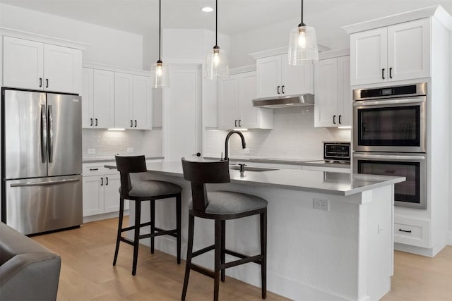 744 Buffalo Trl, Liberty Hill, TX 78642 - kitchen with appliances with stainless steel finishes, under cabinet range hood, backsplash, a kitchen breakfast bar, and white cabinetry