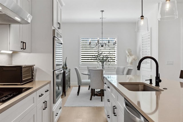 744 Buffalo Trl, Liberty Hill, TX 78642 - kitchen with exhaust hood, light wood finished floors, a chandelier, light countertops, and hanging light fixtures