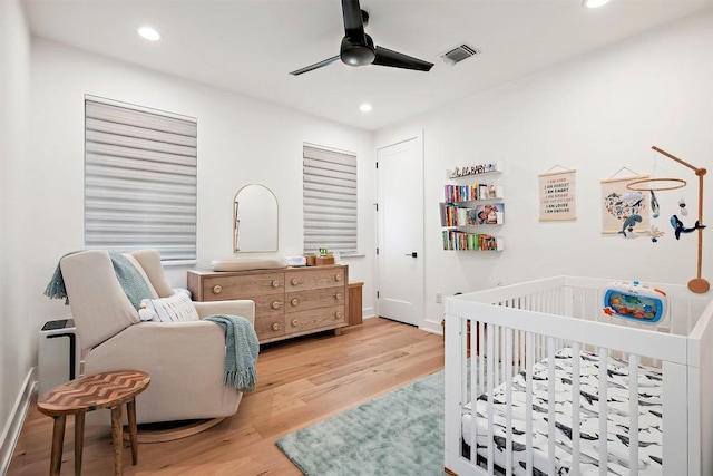 bedroom featuring wood finished floors, visible vents, recessed lighting, and a nursery area