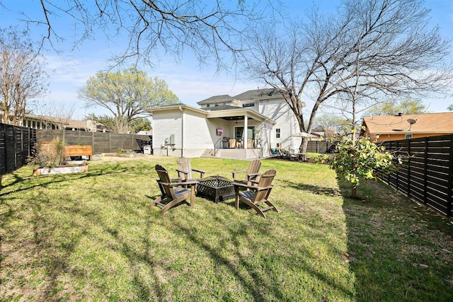 view of yard with ceiling fan, a fenced backyard, and an outdoor fire pit