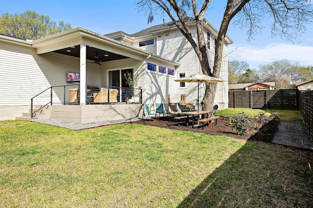 back of property with fence, ceiling fan, and a yard