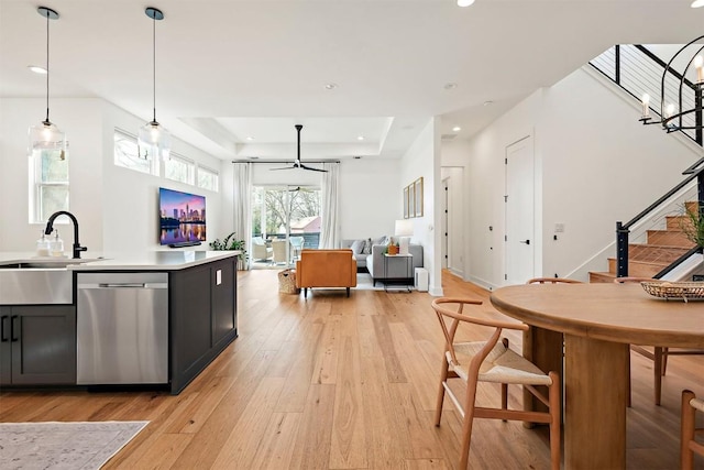 kitchen featuring dishwasher, a sink, light wood-style floors, open floor plan, and ceiling fan