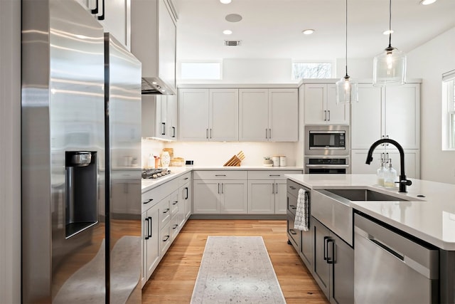 kitchen featuring white cabinets, stainless steel appliances, visible vents, pendant lighting, and light countertops
