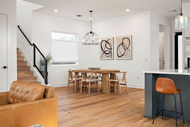 dining room with light wood finished floors, baseboards, a chandelier, and visible vents