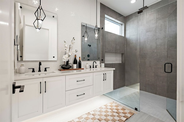 bathroom with tile patterned flooring, a sink, double vanity, and tiled shower