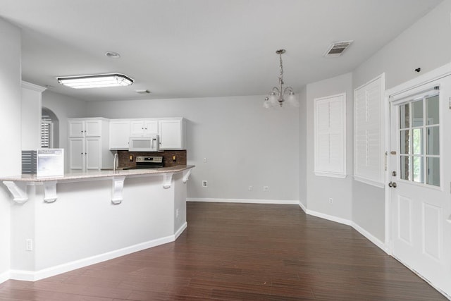 8613 Columbia Falls Dr, Round Rock, TX 78681 - kitchen with white microwave, a breakfast bar, dark wood-style floors, and electric range