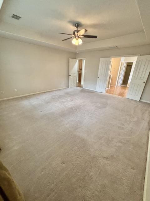 unfurnished bedroom with baseboards, a tray ceiling, and light colored carpet
