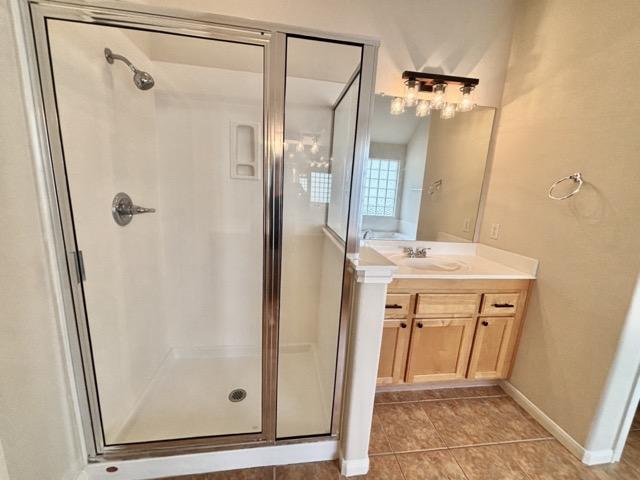 bathroom with tile patterned flooring, vanity, and a shower stall