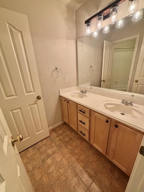 full bathroom with baseboards, double vanity, a sink, and tile patterned flooring