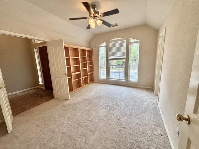 unfurnished bedroom featuring carpet floors, vaulted ceiling, and a ceiling fan