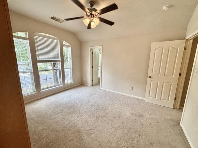 empty room featuring vaulted ceiling, carpet, baseboards, visible vents, and ceiling fan