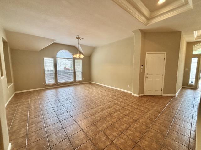 unfurnished room with baseboards, ornamental molding, vaulted ceiling, and a chandelier