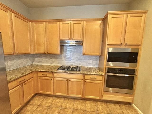 kitchen with stainless steel gas stovetop, under cabinet range hood, light stone countertops, and decorative backsplash