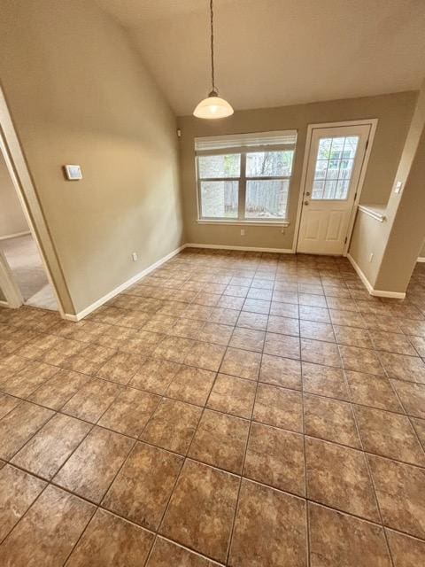 unfurnished dining area with tile patterned floors, baseboards, and vaulted ceiling