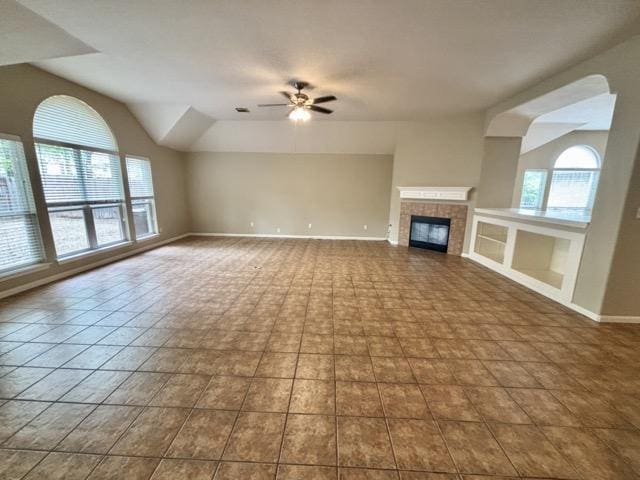 unfurnished living room with baseboards, a tile fireplace, and a ceiling fan