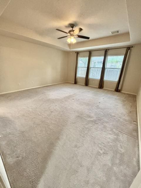 spare room featuring ceiling fan, visible vents, light carpet, and a raised ceiling