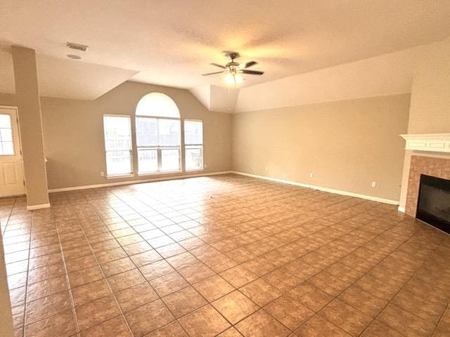 unfurnished living room with lofted ceiling, a healthy amount of sunlight, a tiled fireplace, and a ceiling fan