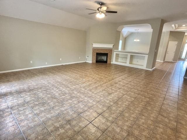 unfurnished living room featuring a fireplace, a ceiling fan, baseboards, and lofted ceiling
