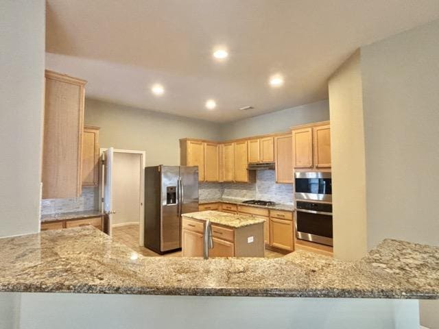 kitchen featuring backsplash, light stone countertops, light brown cabinetry, a peninsula, and stainless steel appliances
