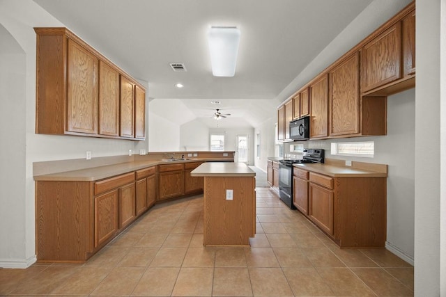 2832 Mission Tejas Dr, Pflugerville, TX 78660 - kitchen with black appliances, a peninsula, brown cabinetry, a ceiling fan, and light tile patterned floors