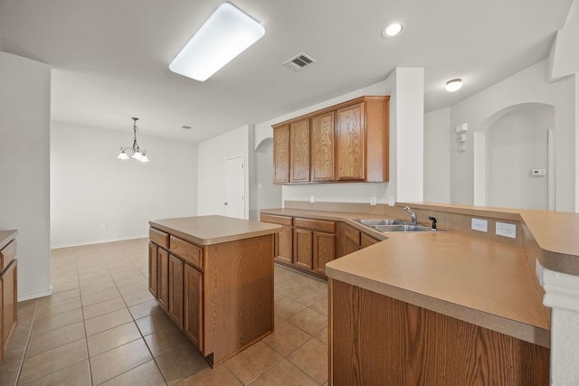 2832 Mission Tejas Dr, Pflugerville, TX 78660 - kitchen featuring arched walkways, a sink, a center island, light countertops, and light tile patterned flooring