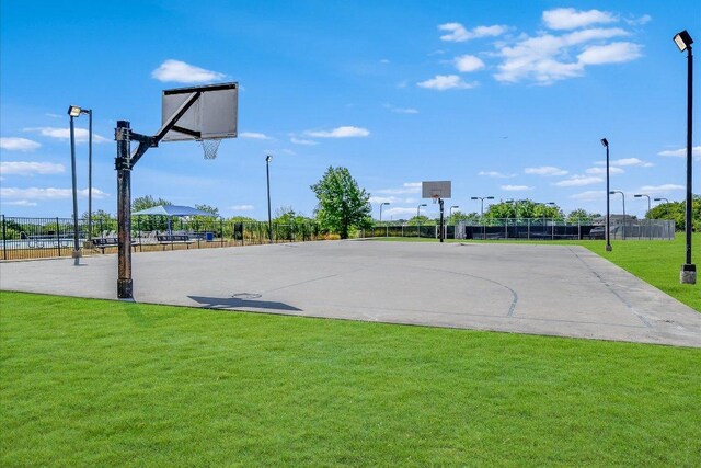 view of basketball court with fence, a yard, and community basketball court