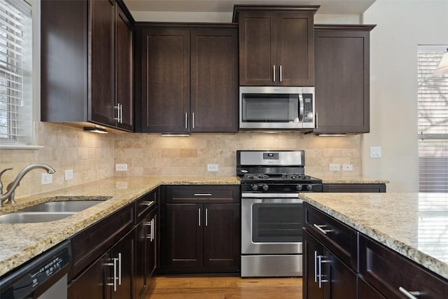 7709 Menchaca Rd Unit 35, Austin, TX 78745 - kitchen featuring appliances with stainless steel finishes, light stone counters, dark brown cabinets, and light wood finished floors