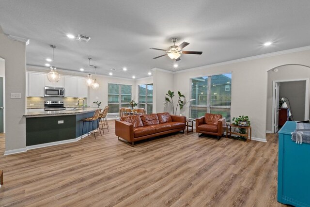 1806 Ashburn Dr, Temple, TX 76502 - living room featuring recessed lighting, ornamental molding, light wood finished floors, ceiling fan, and arched walkways