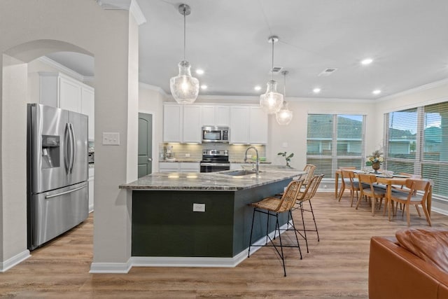 1806 Ashburn Dr, Temple, TX 76502 - kitchen featuring appliances with stainless steel finishes, crown molding, light stone countertops, arched walkways, and white cabinets