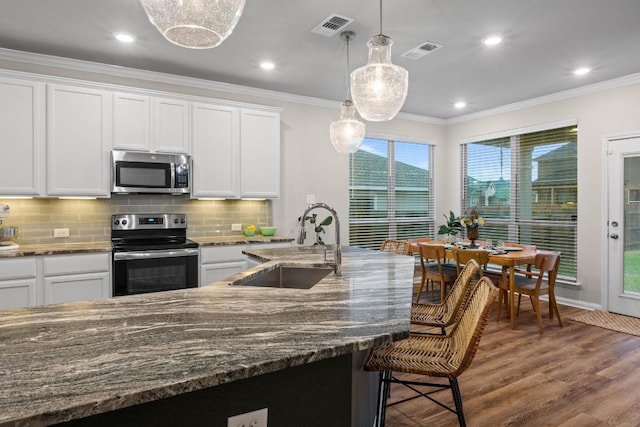 1806 Ashburn Dr, Temple, TX 76502 - kitchen with appliances with stainless steel finishes, wood finished floors, decorative backsplash, dark stone counters, and crown molding