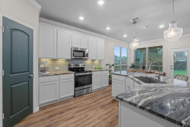 1806 Ashburn Dr, Temple, TX 76502 - kitchen with stainless steel appliances, ornamental molding, white cabinetry, backsplash, and light wood finished floors
