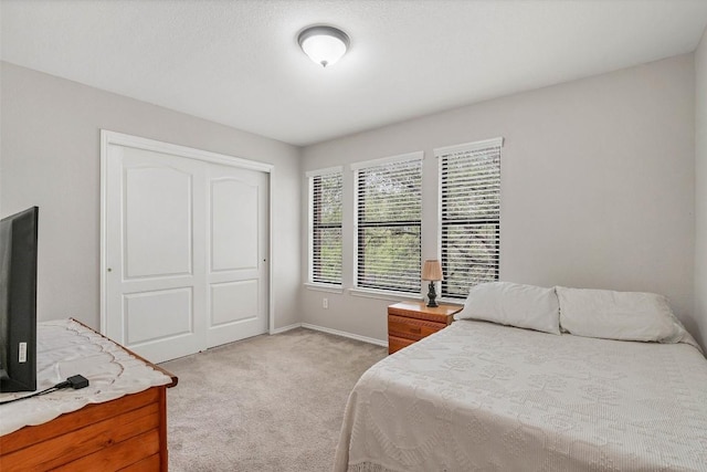 bedroom featuring a closet, baseboards, and light carpet
