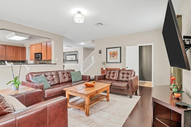living room with stairway, wood finished floors, and visible vents