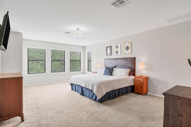 bedroom with baseboards, visible vents, and light colored carpet