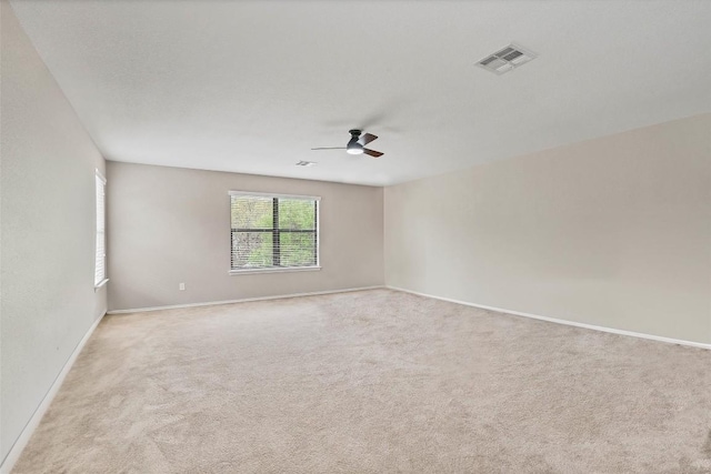 empty room with baseboards, visible vents, carpet floors, and ceiling fan