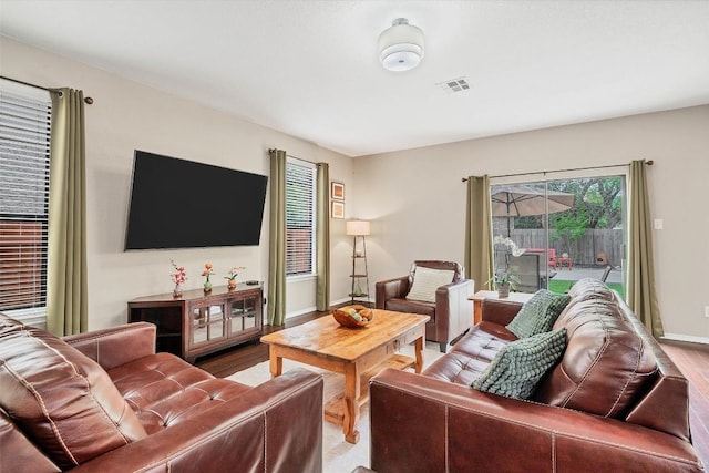 living area featuring baseboards, wood finished floors, and visible vents