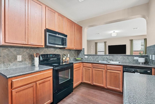 kitchen with a sink, stainless steel microwave, visible vents, wood finished floors, and black / electric stove
