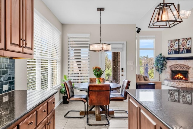 3925 Good Night Trl, Leander, TX 78641 - dining area featuring a stone fireplace, light tile patterned flooring, and baseboards